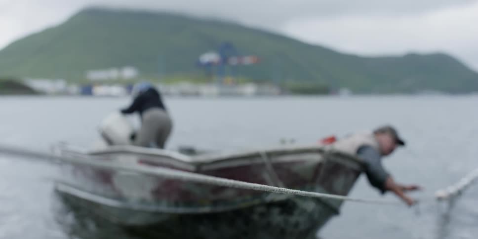 Two fishermen float in a boat
