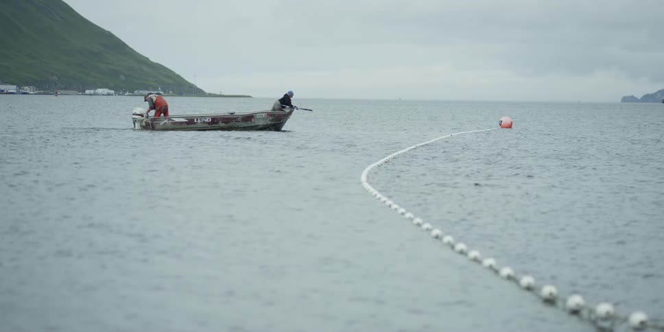 Two fishermen float in a boat