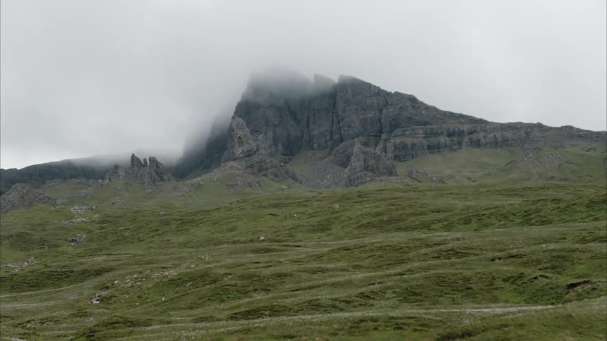 Clouds hover over a rocky cliff