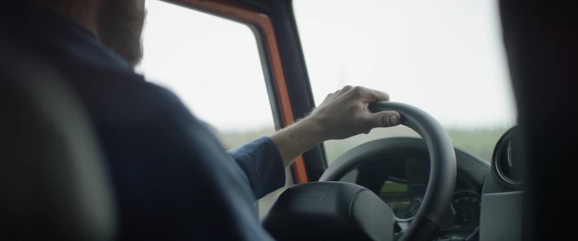 A man is driving his car on a cloudy day