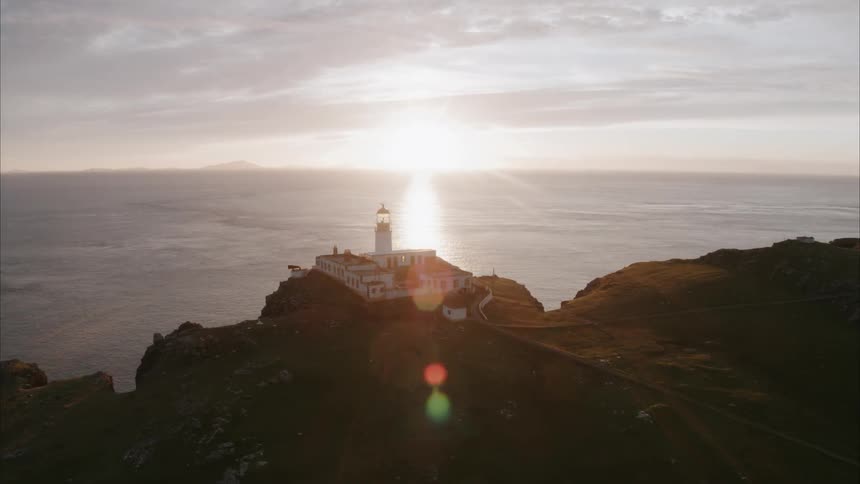 The sun sets over a coastal lighthouse