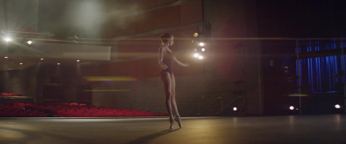 A ballerina dances on a stage in an empty theater