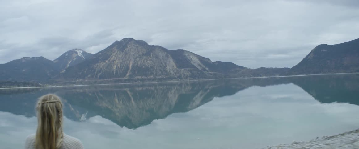 A woman looks at a mountain lake