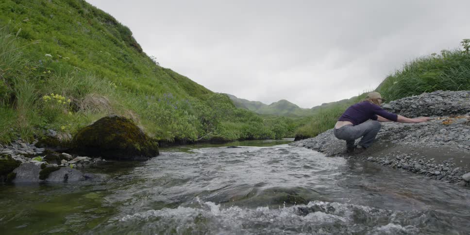 A man jumps across a small creek