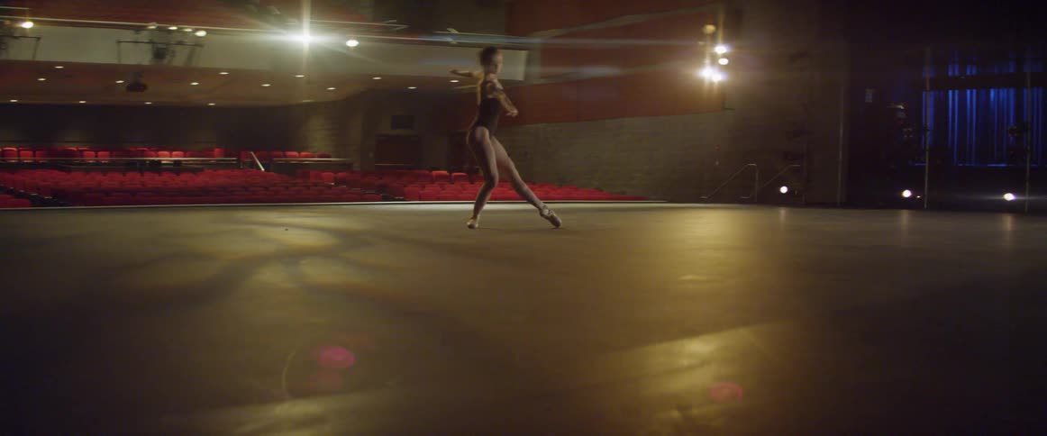 A woman is dancing on the dark stage