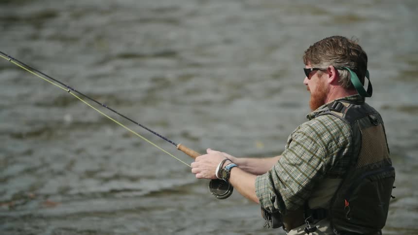 A man casts a fishing line into a river