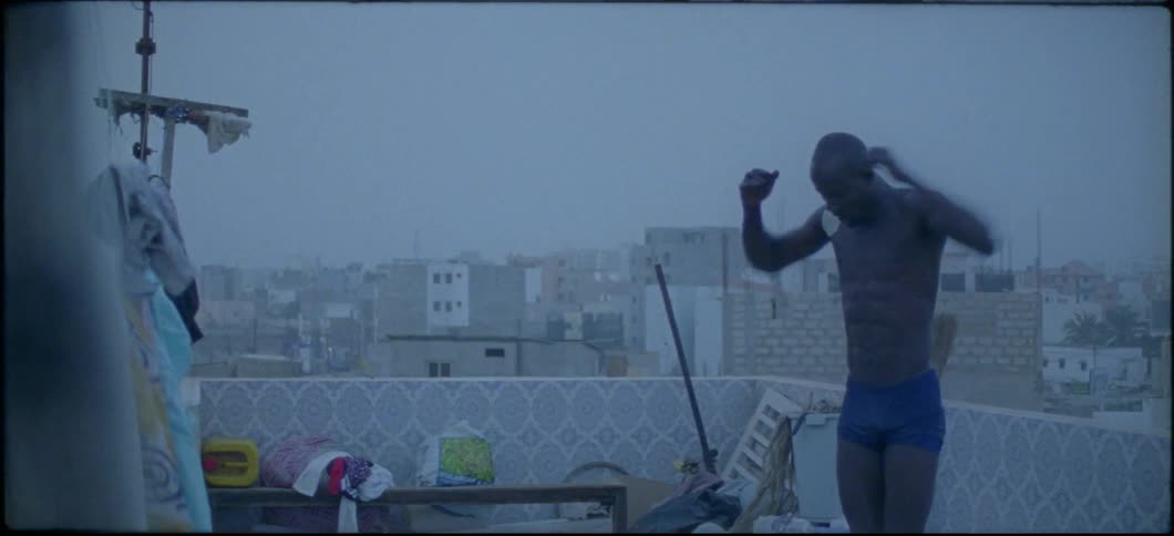 A man on a rooftop patio stretches his arms and shoulders