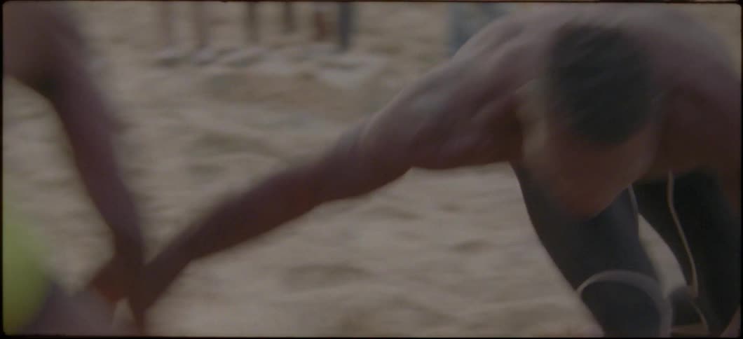 Two men wrestle in sand