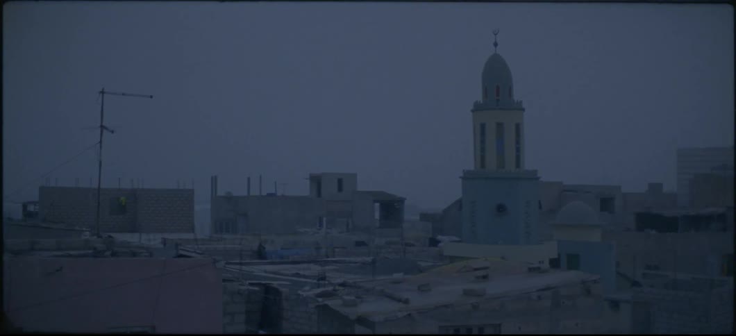 The wind blows a tarp on a rooftop near a church in a poor neighborhood