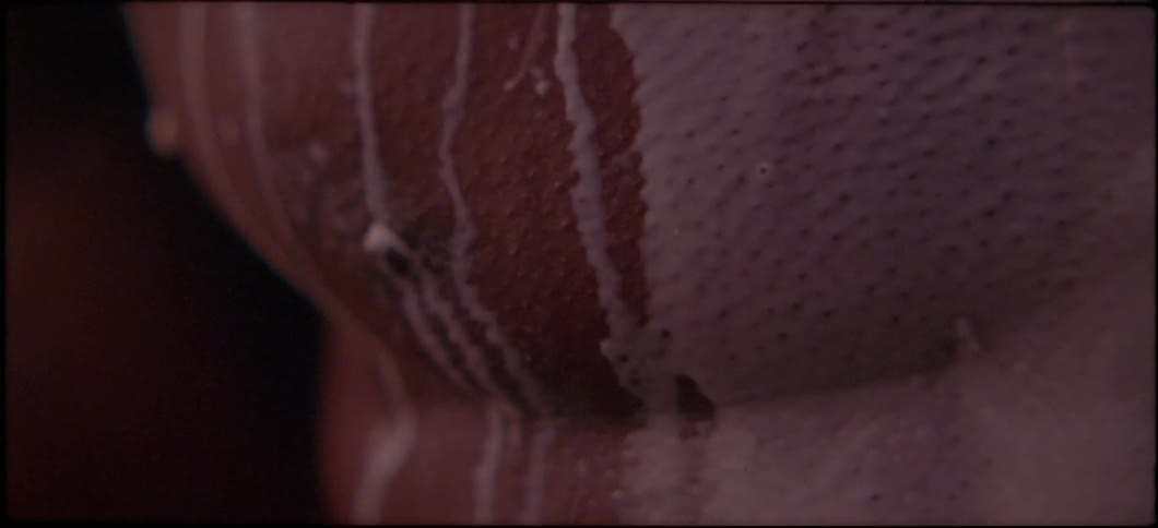 A white liquid drips down a man's bare chest and nipple