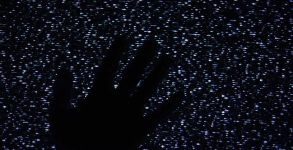 Closeup of a hand touching a static riddled television set
