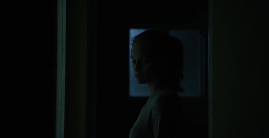 Woman stands contemplating in a dark room