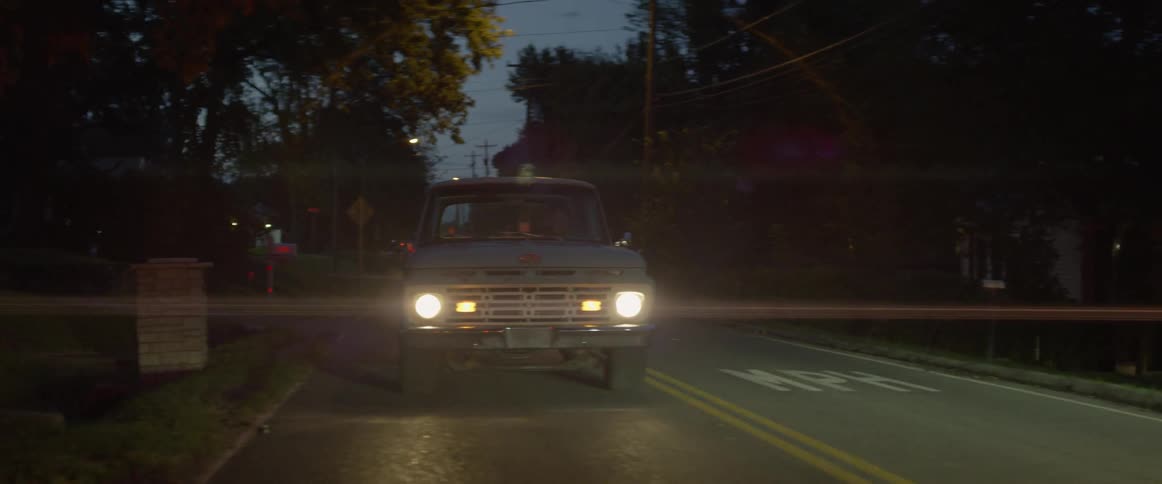 A truck drives down a road at dusk