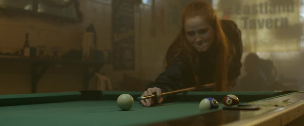 A woman lines up a pool shot and misses