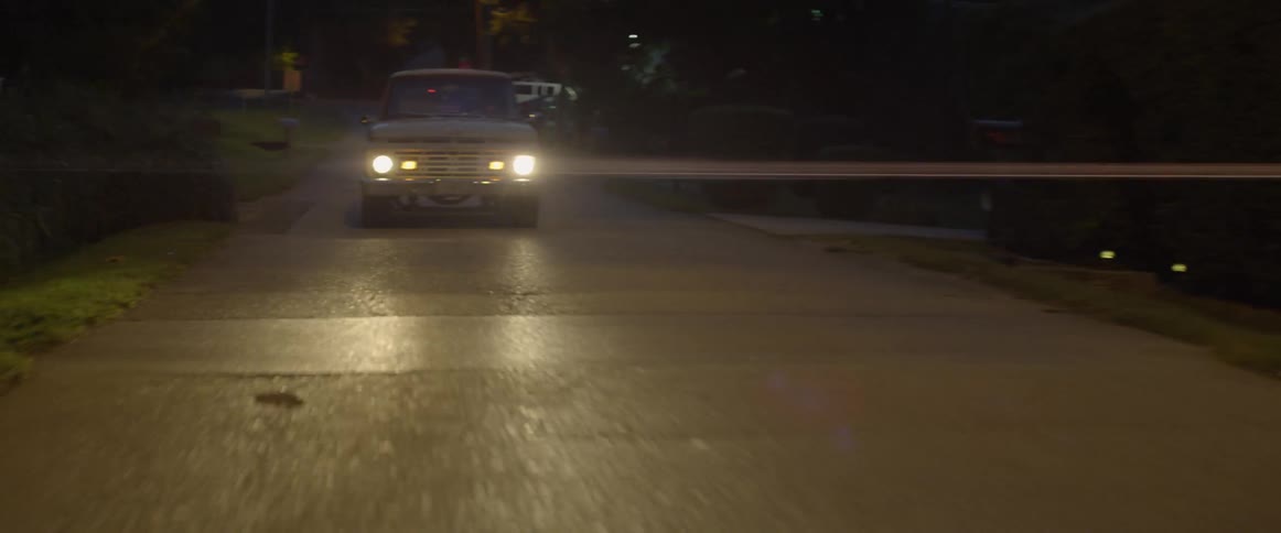 A truck drives down a street at night