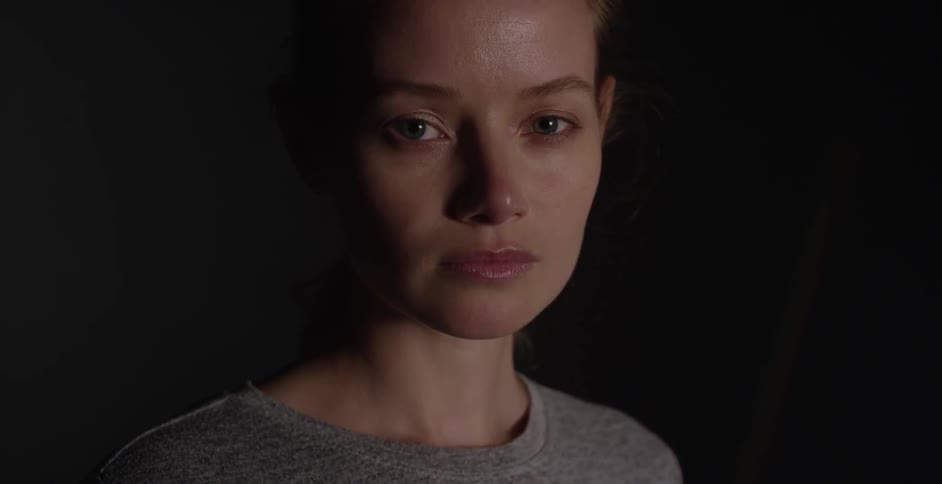 A woman in a gray shirt opens her eyes