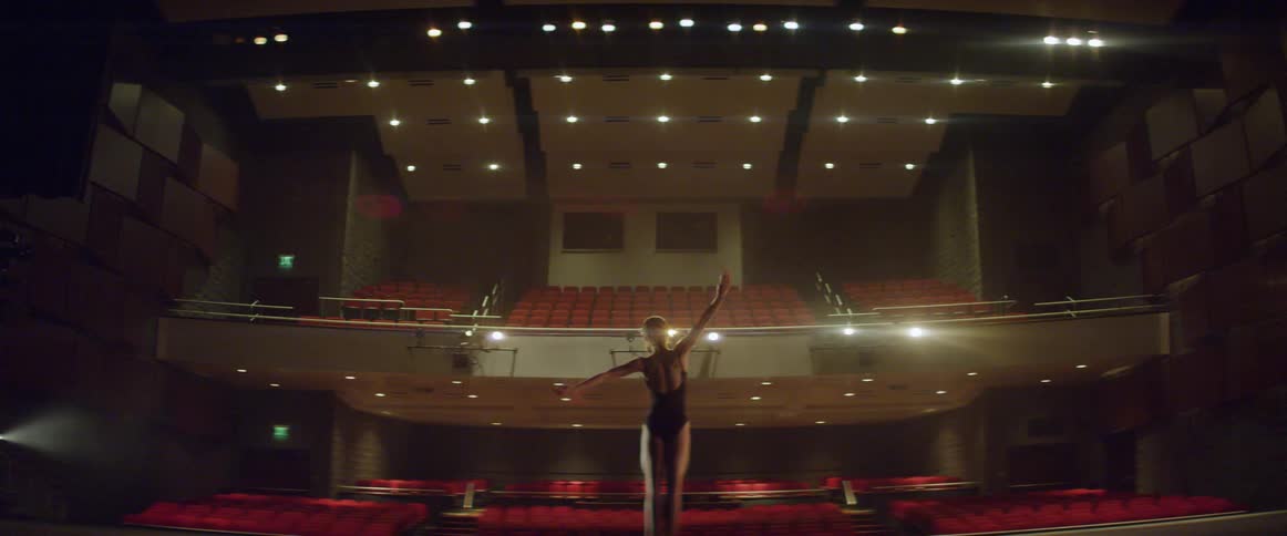 A woman is performing ballet on stage for no audience