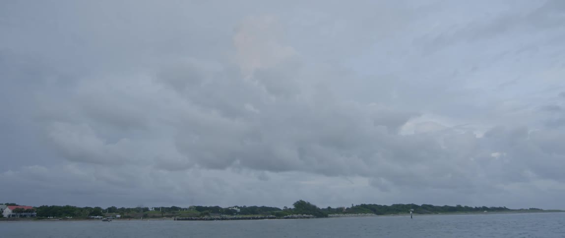 White clouds hang over the ocean shoreline