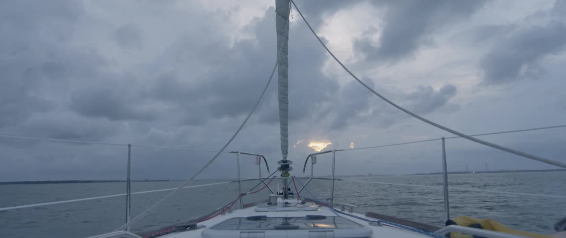 The bow of a sailboat on the ocean at sunset