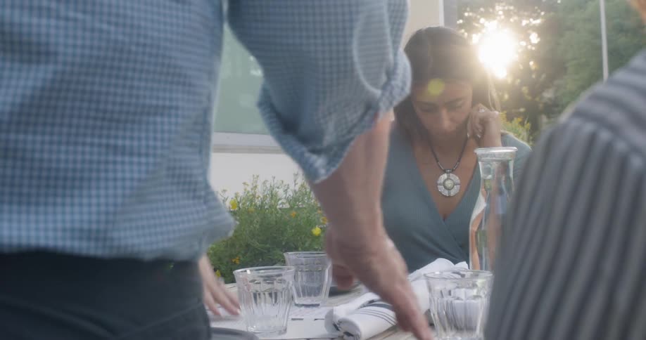 Four women sit at an outdoor table talking with a waiter