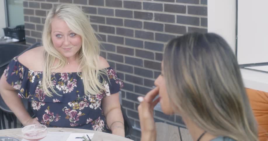 A group of women are sitting at a table having a conversation while eating