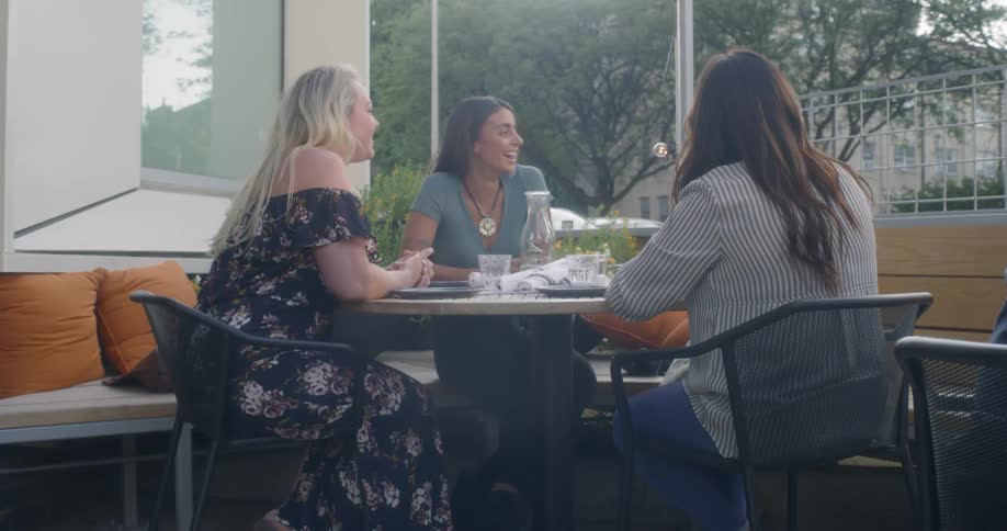 Four women sit at an outdoor table talking