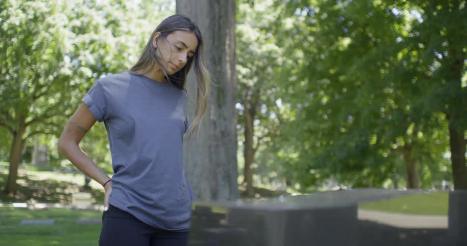 Woman stands and studies a gravestone