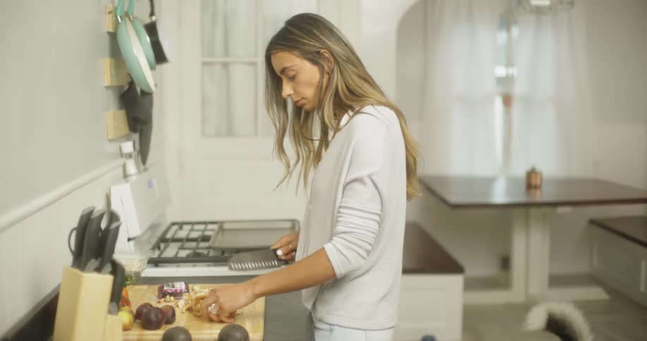 A woman is chopping up food on a cutting board