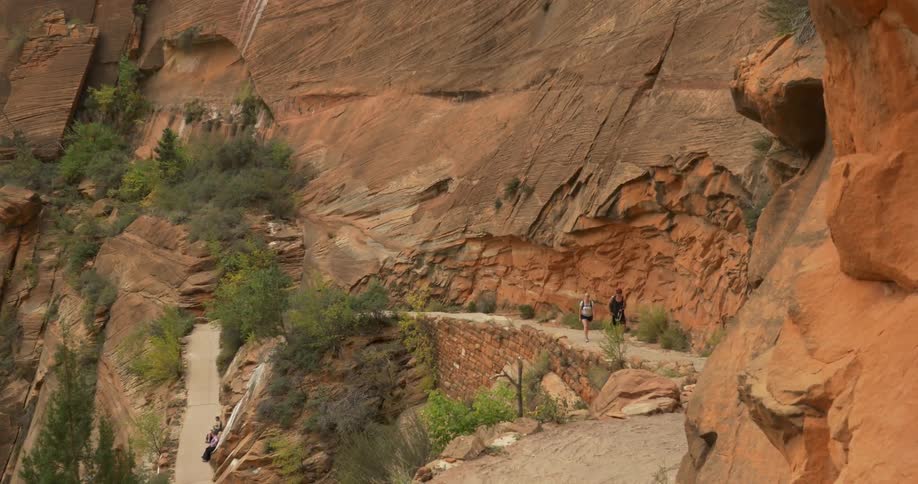 People walking down a trail next to a steep mountain