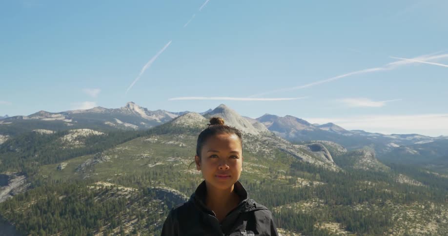 Woman stands in front of a mountain range