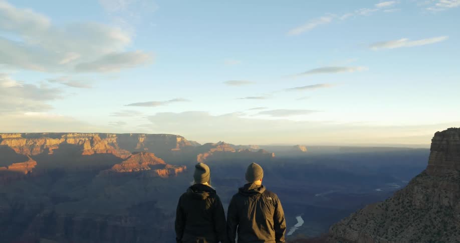 Two people standing on a mountain peak seeing a nice view