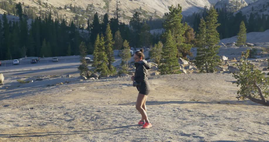Girl walking uphill with mountains behind her