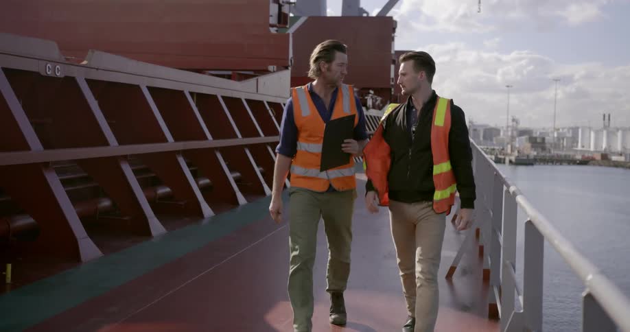 Two workers walk on a ship deck