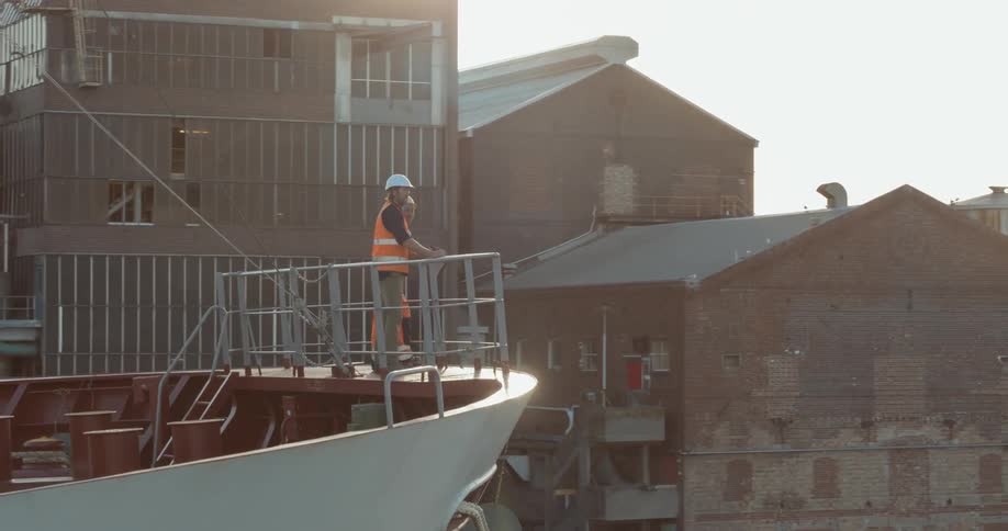 Two construction workers stand on a docked ship