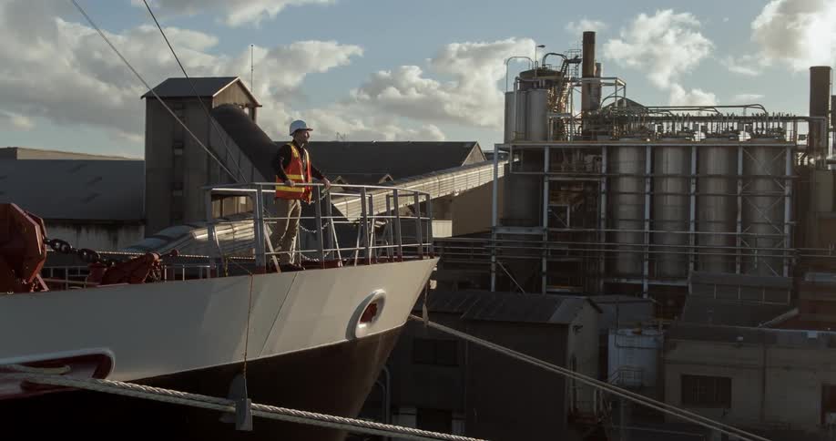 A construction worker leans on the rail of a large ship