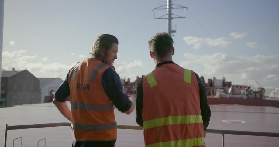 Two workers talk while standing on a ship