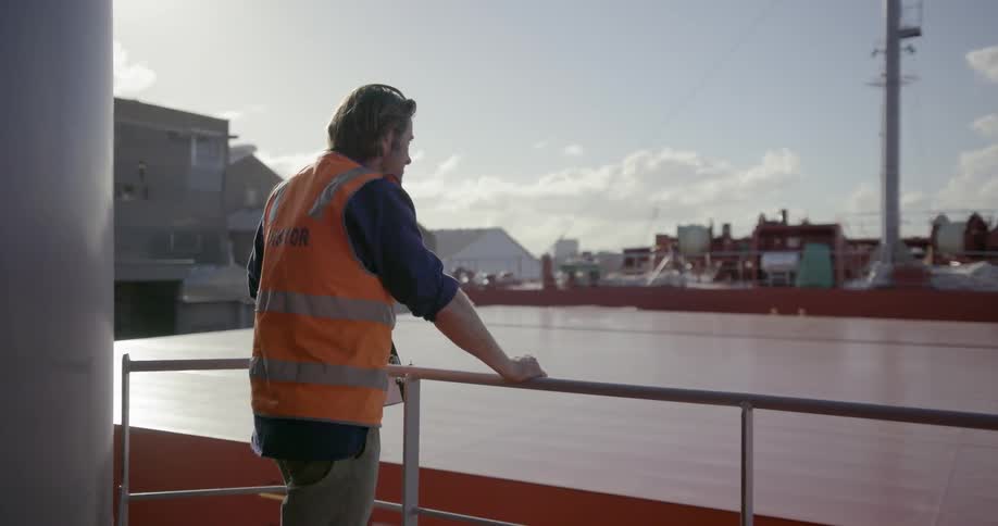 A worker stands next to a rail on a ship