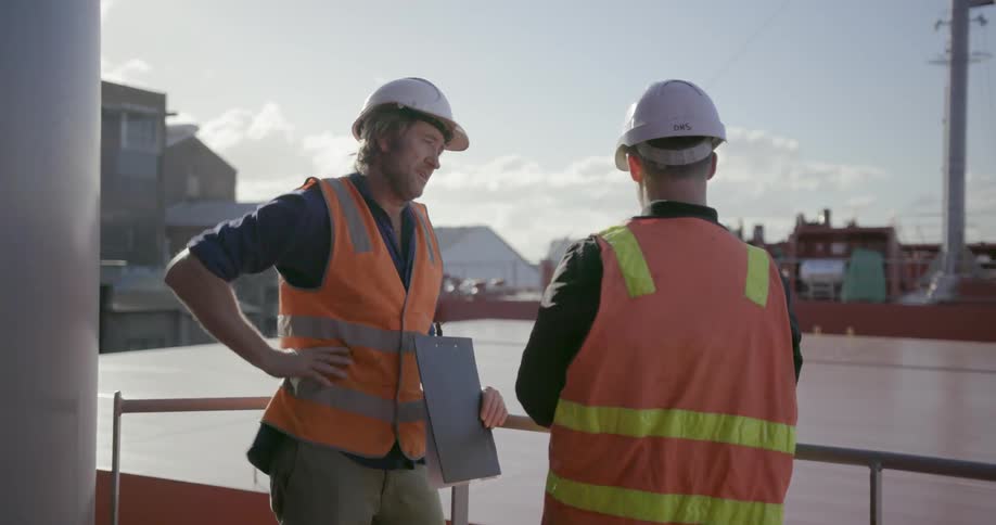 Two workers talk while standing on a ship