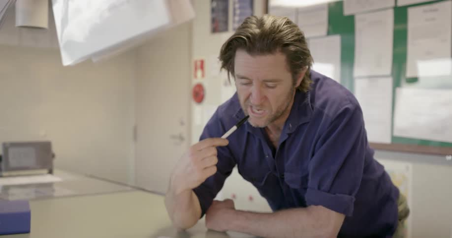 A man is writing something down in a book with an ink pen