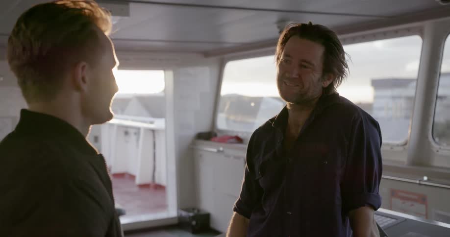 Two men talk on a boat