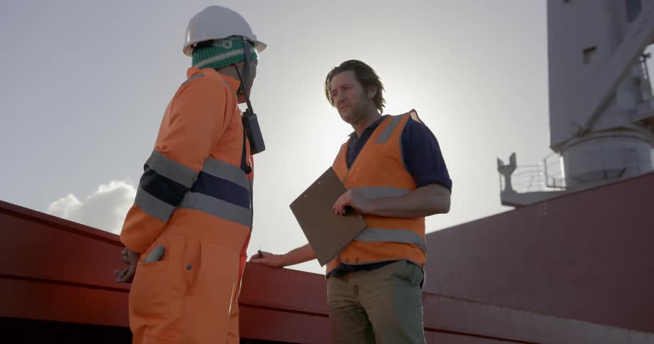 Two workers talk while standing on a ship