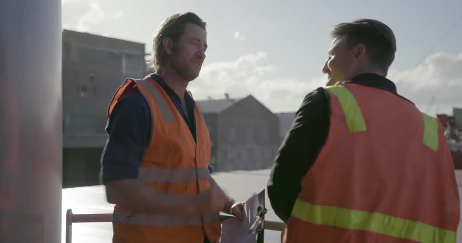 Two workers talk while standing on a ship