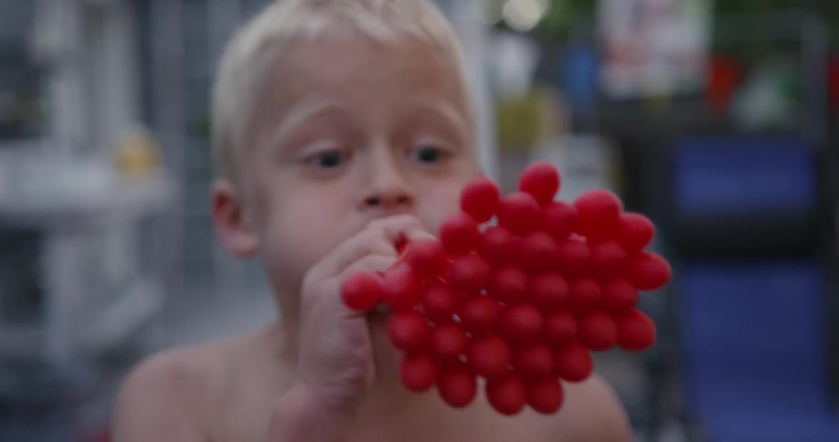 Child blows up many small balloons at once