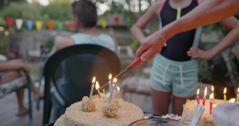 Person lights candles on a cake outside