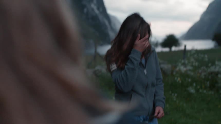 A couple of women are putting up a tent next to a large mountain