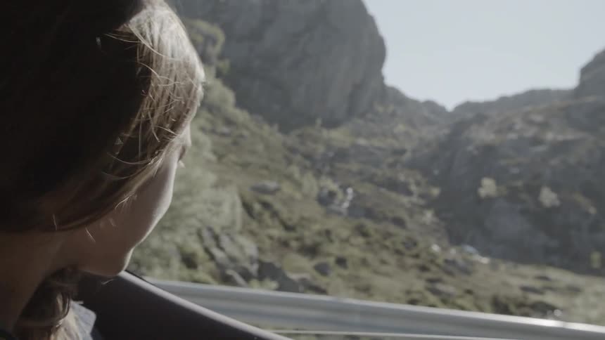 Girl rides in a car in the mountains with her window down