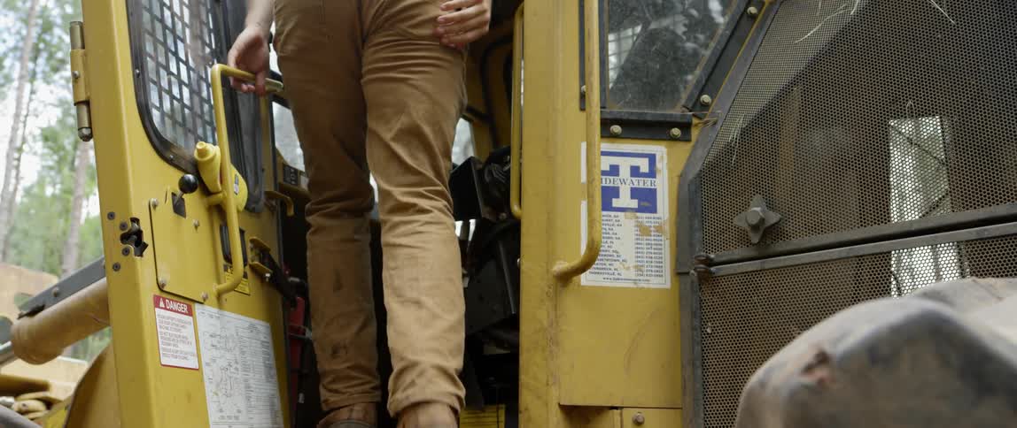 Someone is climbing into the cab of a piece of heavy machinery