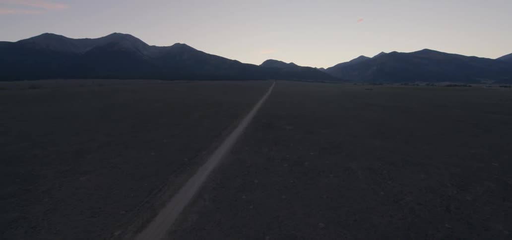 Long straight road heading into mountains in the wilderness