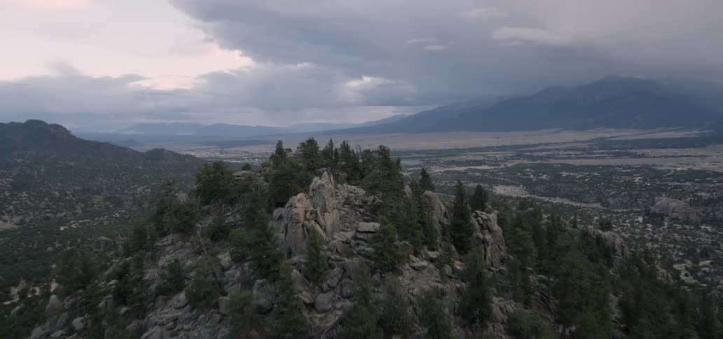 Storm clouds hang over a desert valley and hills