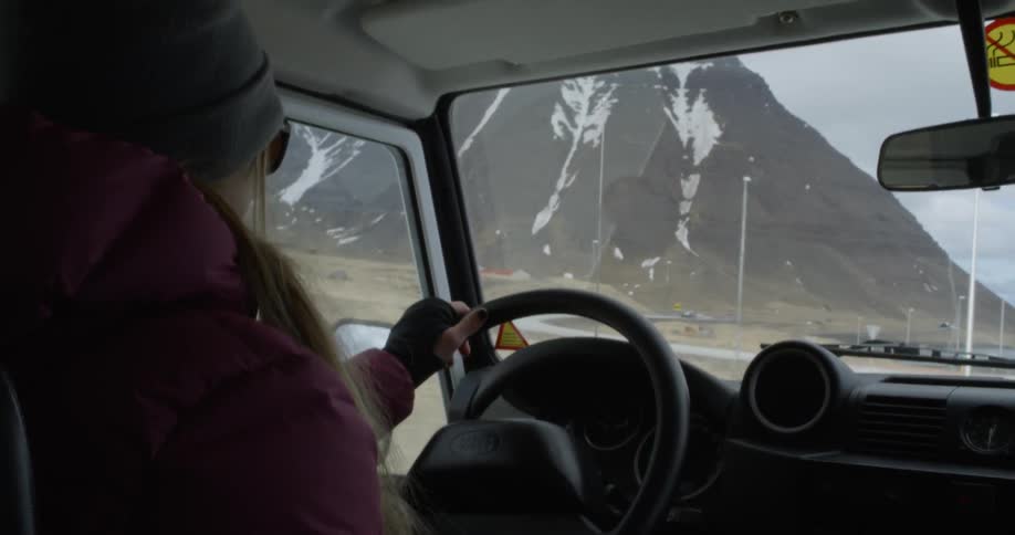 Person drives a vehicle on a road near mountains